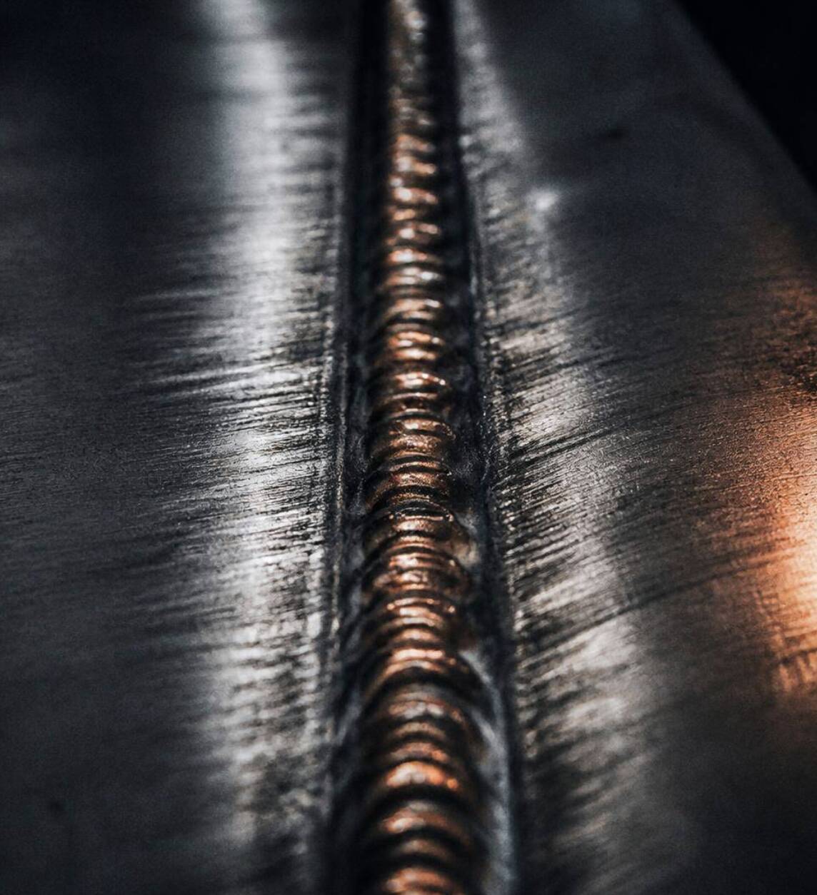 Close-up of a TIG weld on a stainless steel cabinet joint